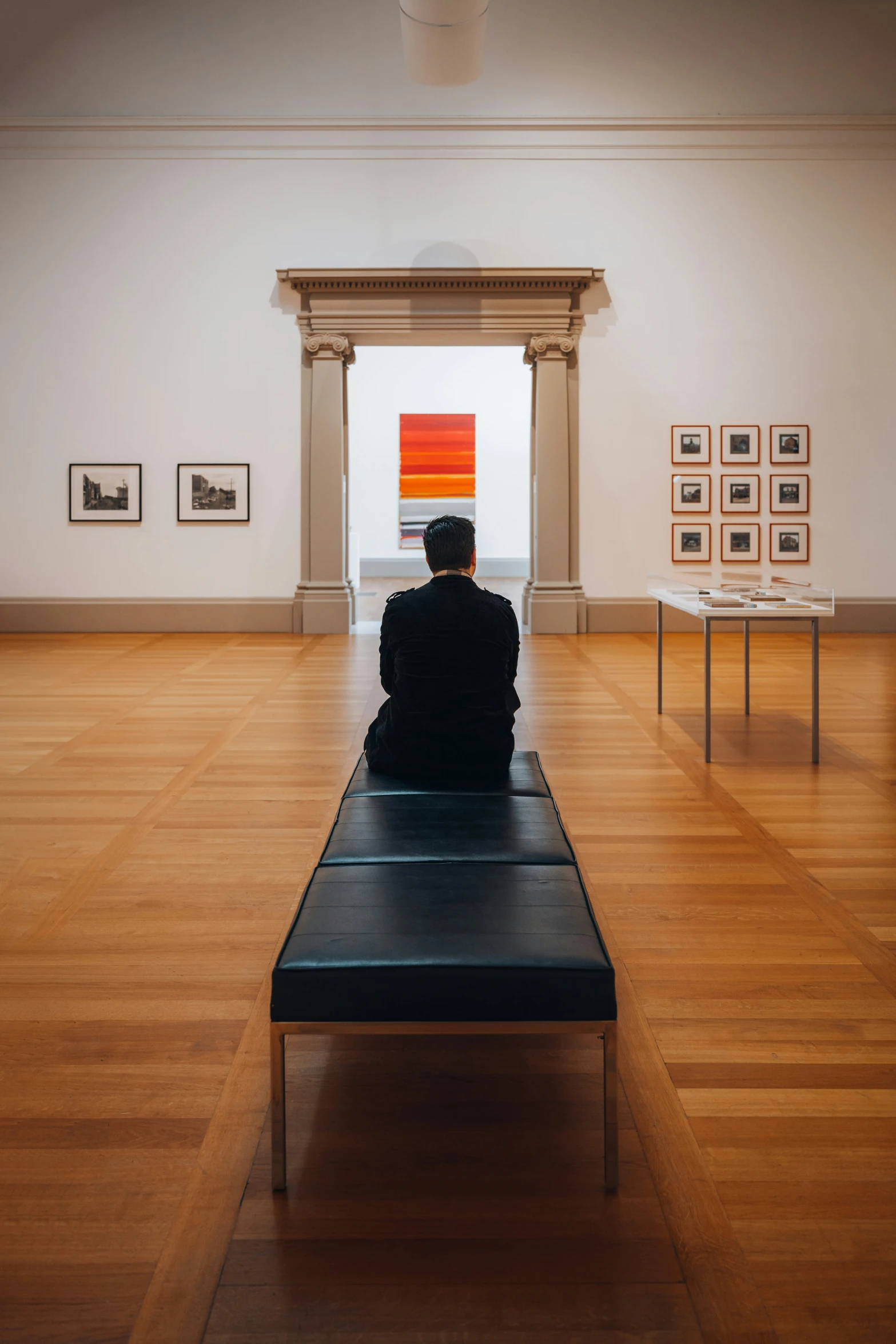 person sitting on a bench in an empty room with art