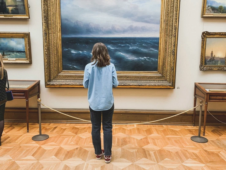 women in a museum looking at a painting