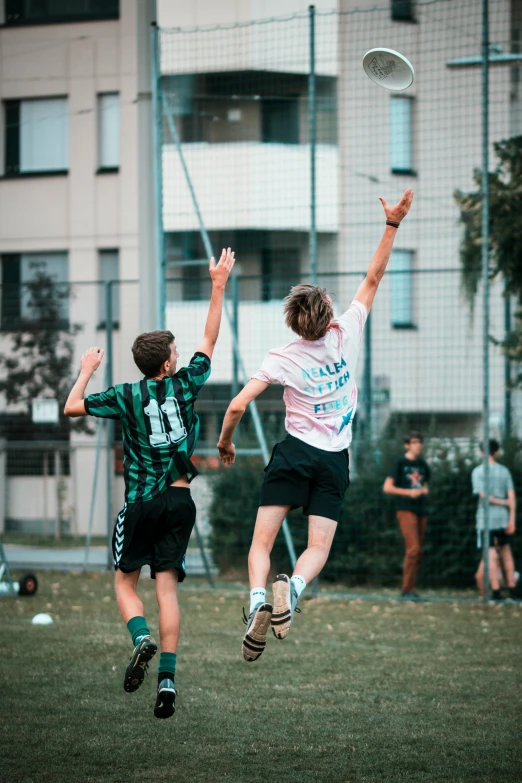 two men jumping for the frisbee while others watch