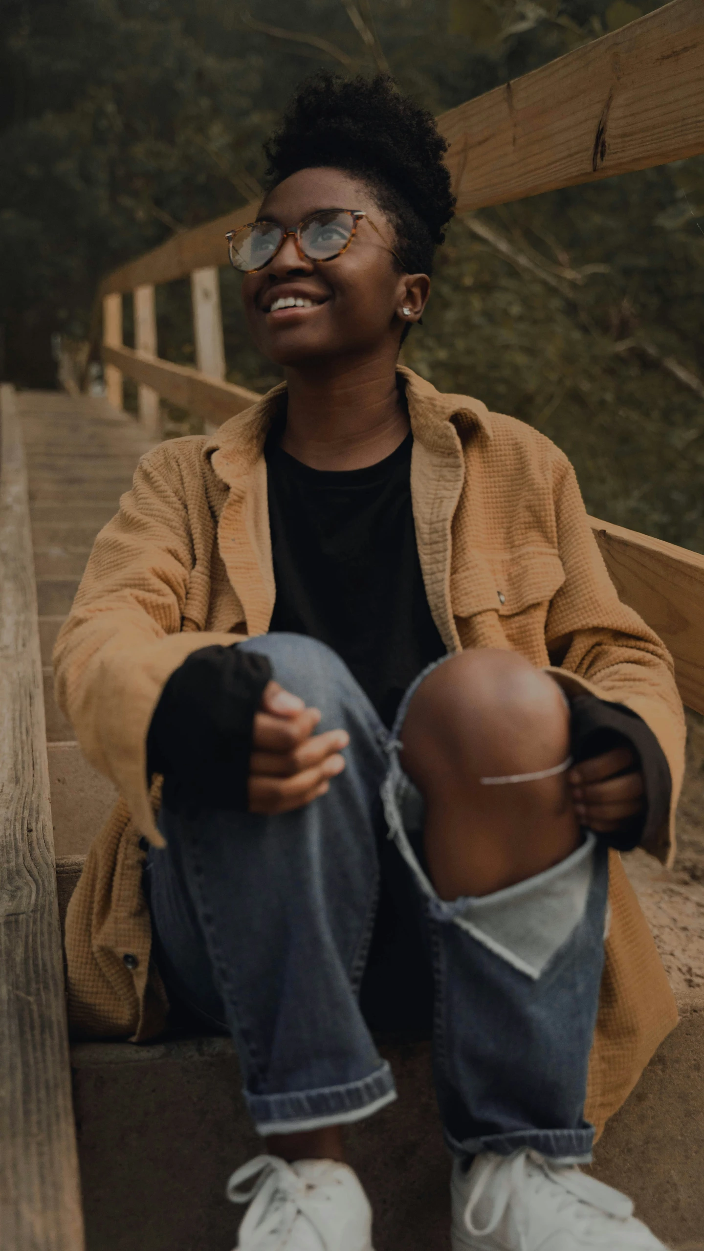 a smiling man with a baseball cap on sitting on stairs