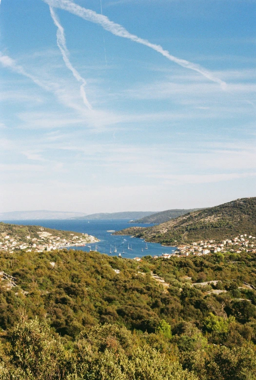 a view from a hilltop, looking down on a lake and several islands
