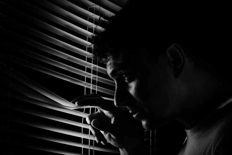 a young man in black and white looking out of a window