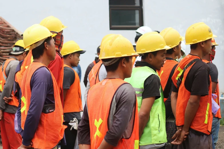 a large group of workers standing around in front of a building