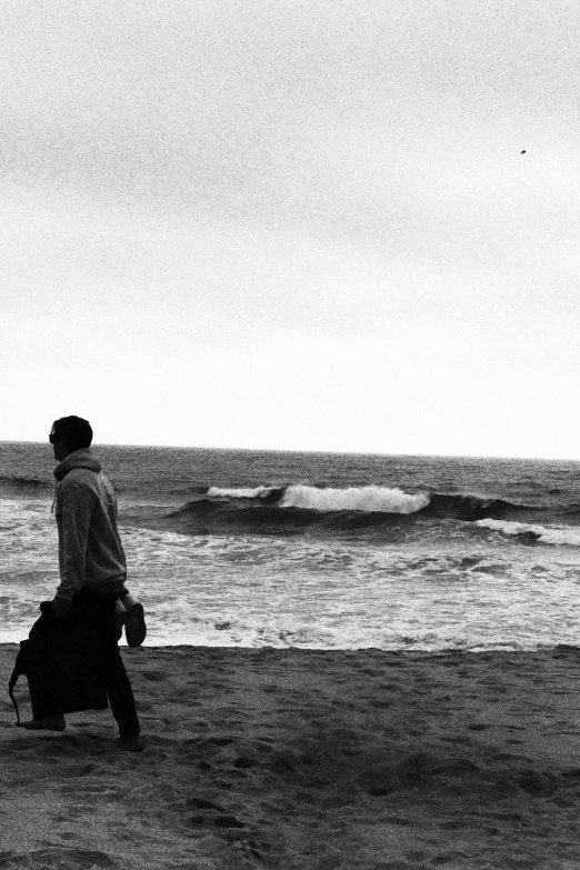 a man walking down a beach carrying a piece of luggage