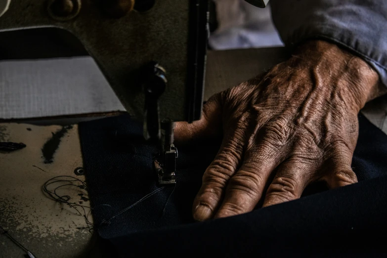 a pair of hand on fabric next to machine