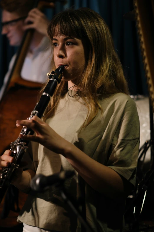 a woman playing a trumpet with another musician in the background