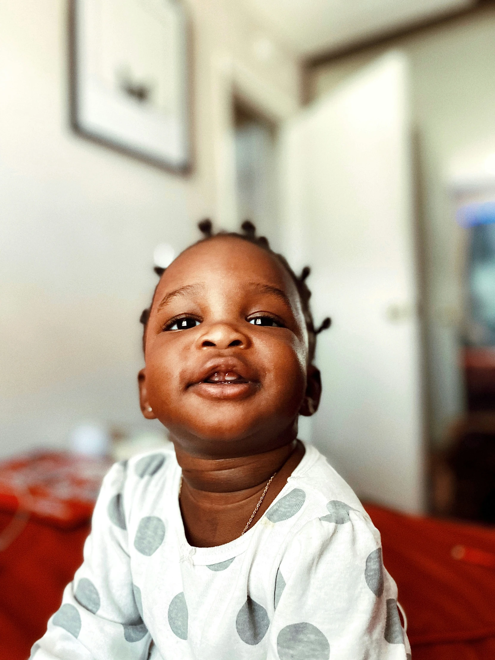 a baby sitting on a bed with two hair sticking out