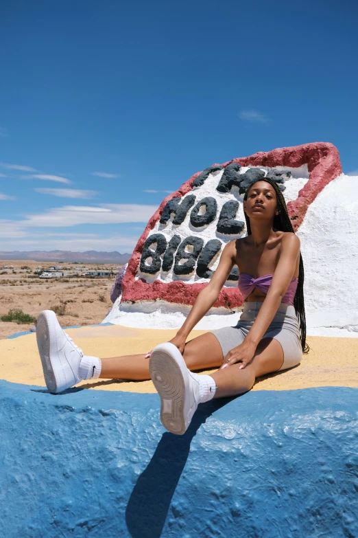 woman sits on top of a stone art piece in the desert