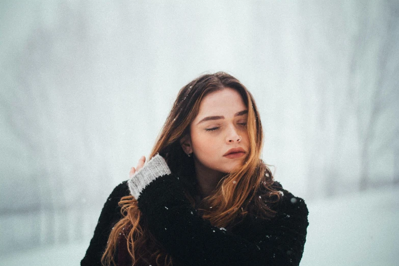 a woman is standing in the snow blowing her hair