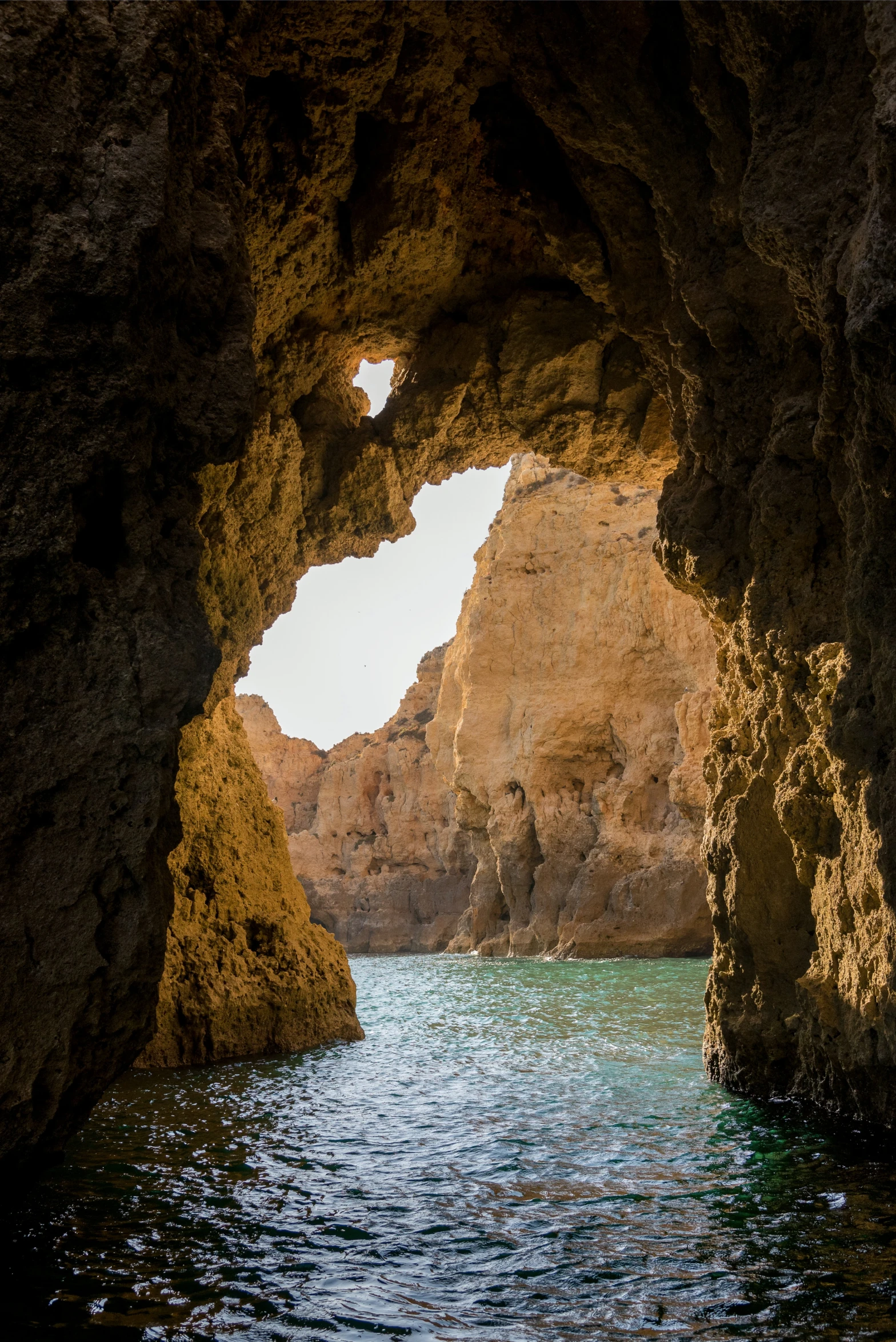 a large cave next to the ocean in front of some rocks