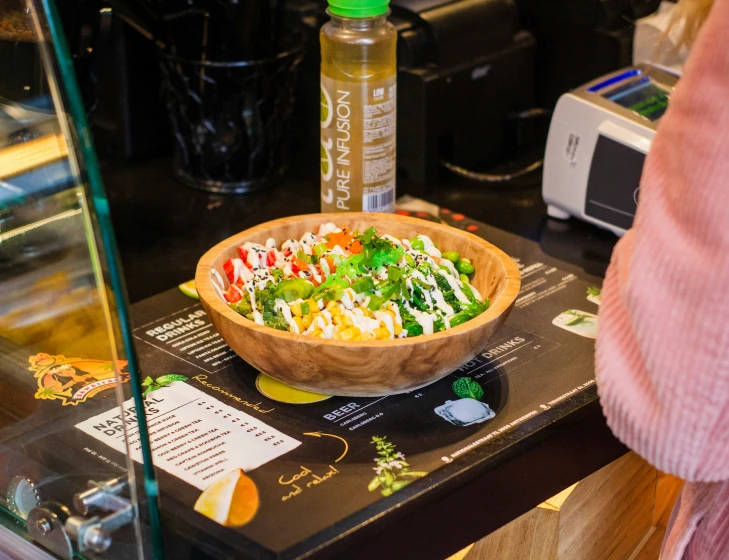 a person is holding a bowl filled with salad