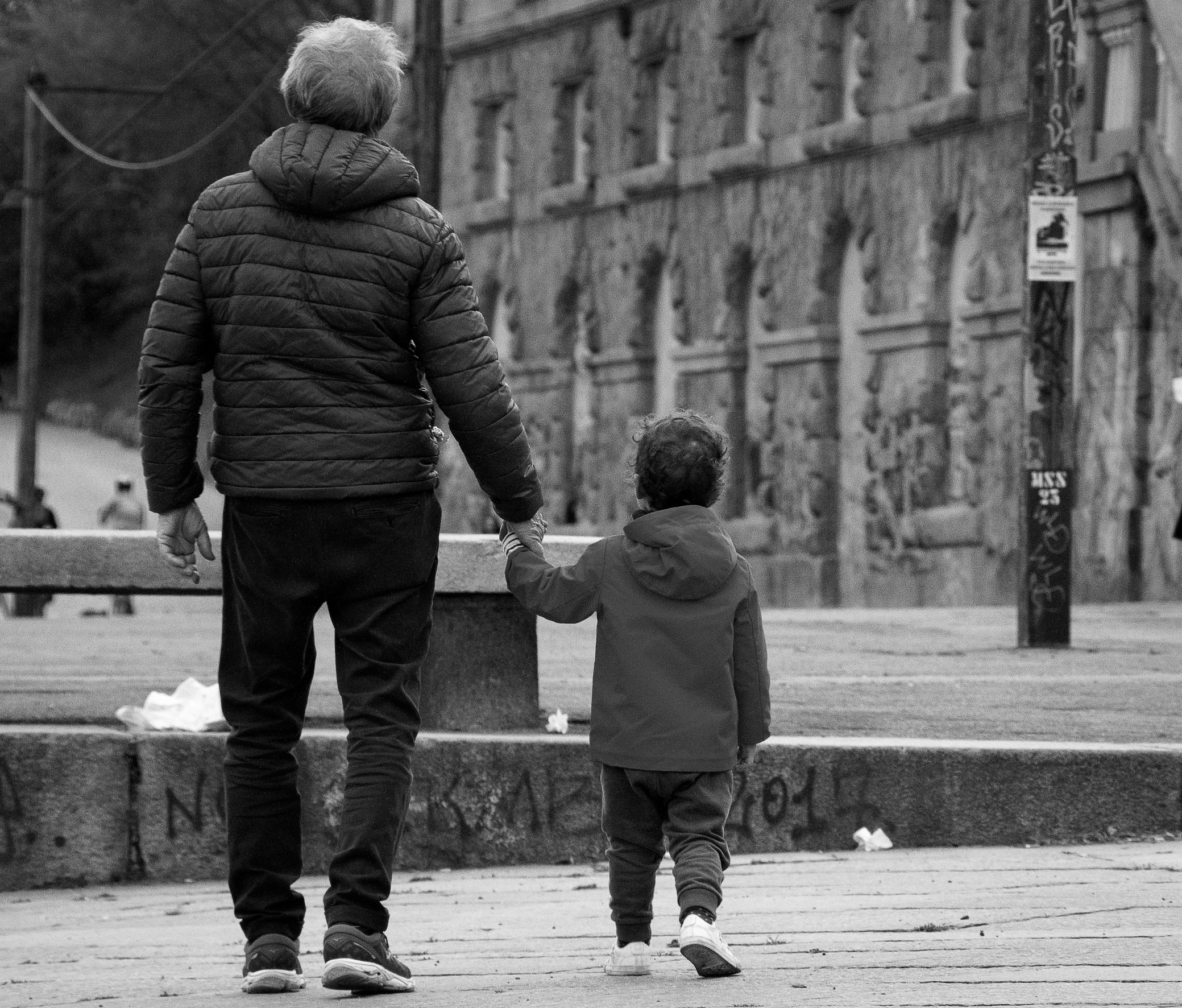 a man and his child walk down a street