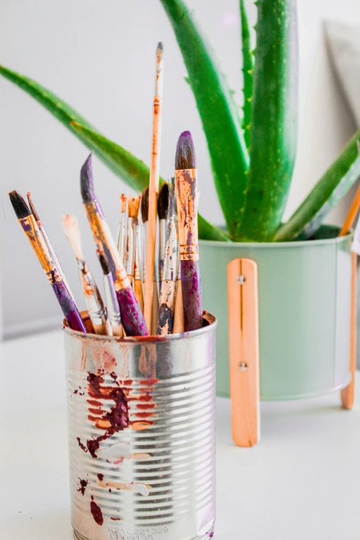 an old tin can is filled with paint brushes