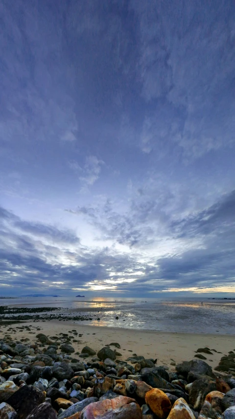 a bench on a rocky beach at sunset