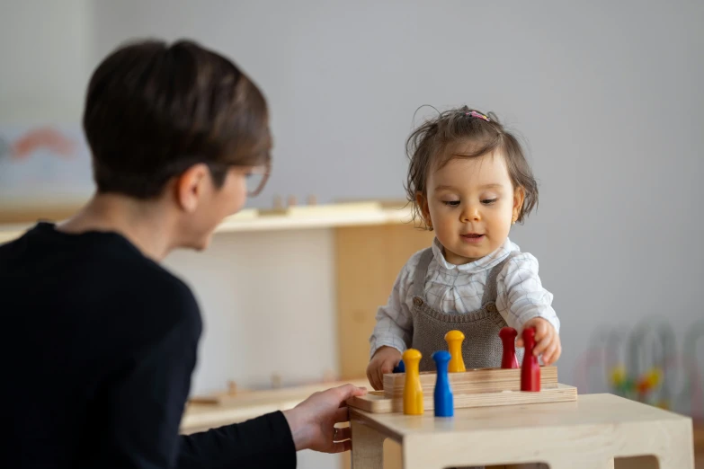 there is a woman standing in front of a table with wooden pegs