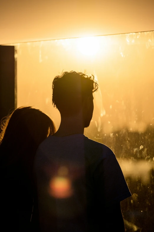 the sun is setting in front of the horizon, as two people are silhouetted