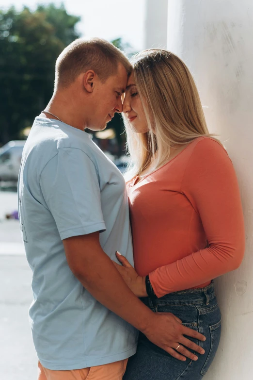 a couple looking at each other as they lean against a column