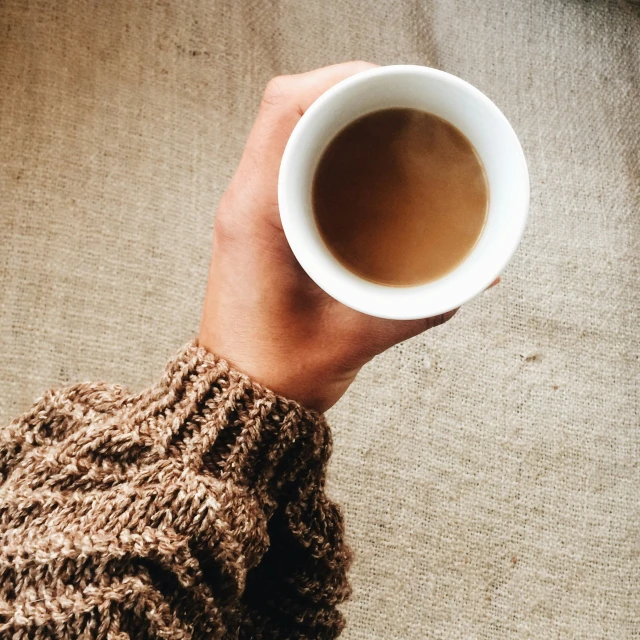 someone holding a cup of coffee in their hand