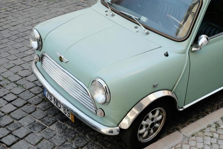 the small green car is parked on the curb