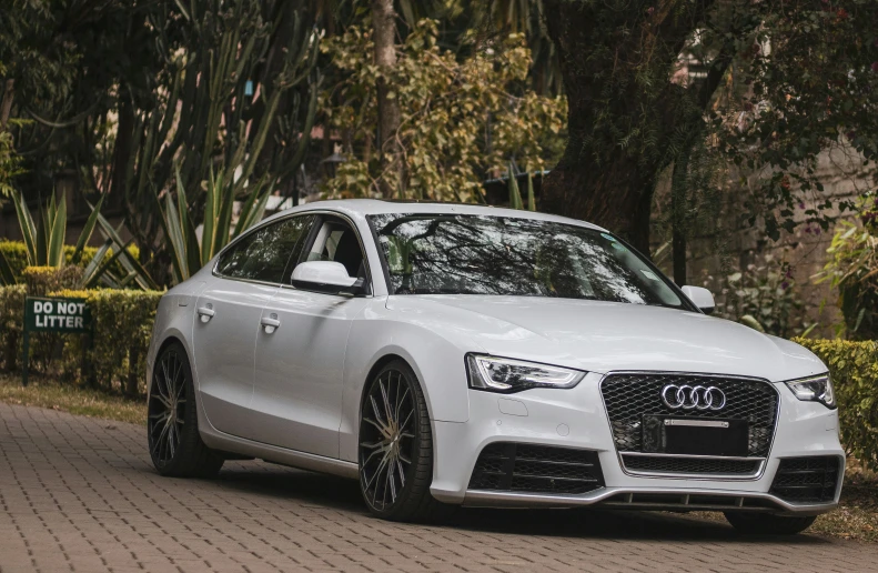 the front view of a white car parked on a brick road