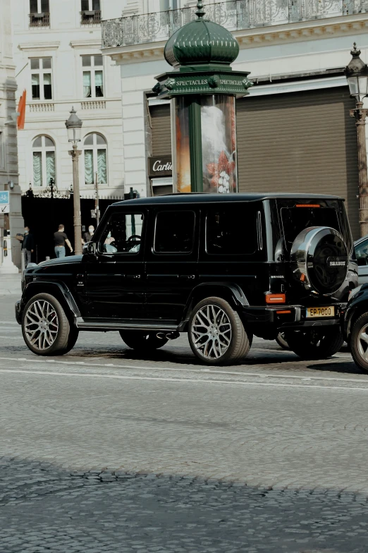 a range rover car and a hummer truck driving down the street