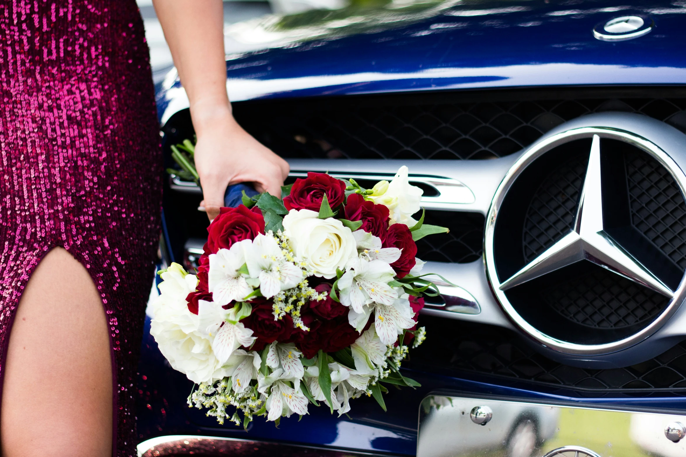 bride holding bouquet near mercedes logo at outdoor event