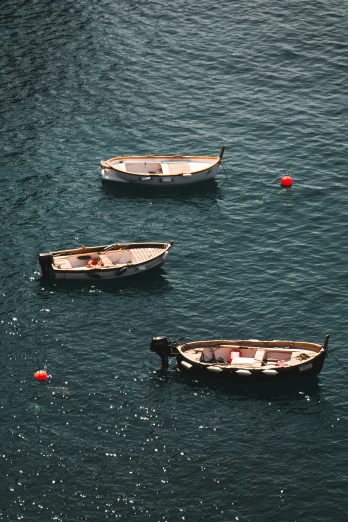 three small boats floating in the ocean together
