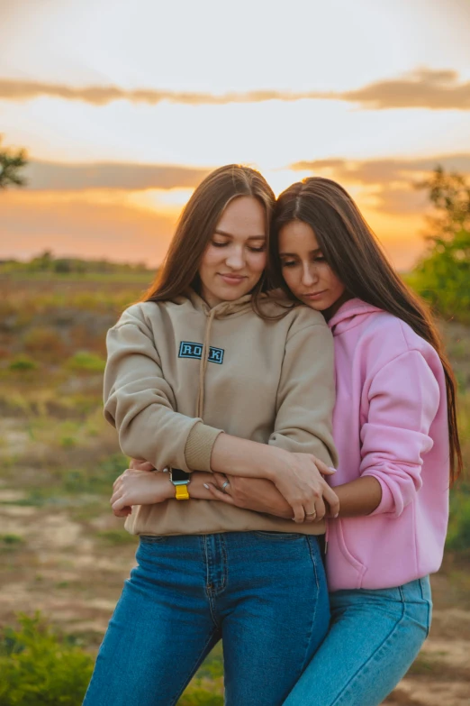 two girls emcing each other while the sun sets