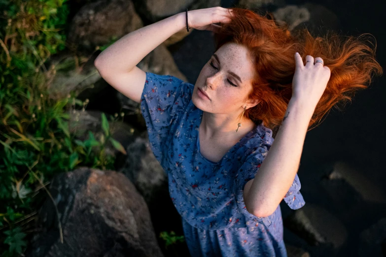 a red - haired woman poses with her hair in a motion