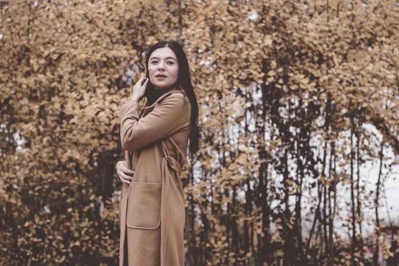 a woman talking on her cell phone next to a tree