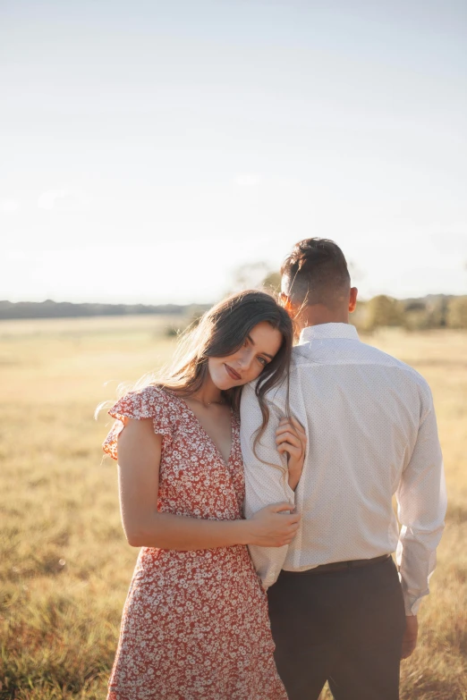 an adult couple standing next to each other in a field of tall grass