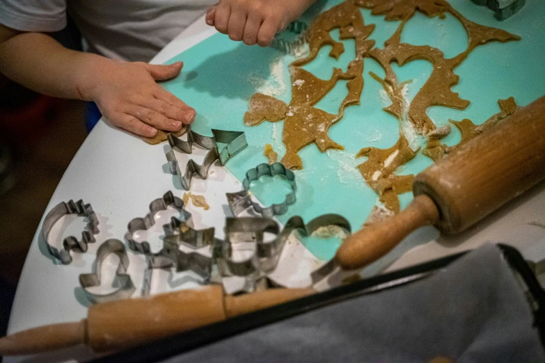 a child is making cookie items on a wooden table