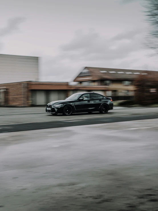 the black car is driving in front of a building