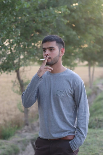 a man smoking a cigarette in front of a tree
