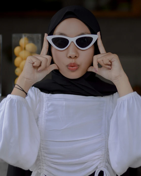 an asian woman wearing white clothes holds her hands up in the air