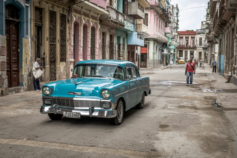 people walking in an alley where many old cars and buildings are seen