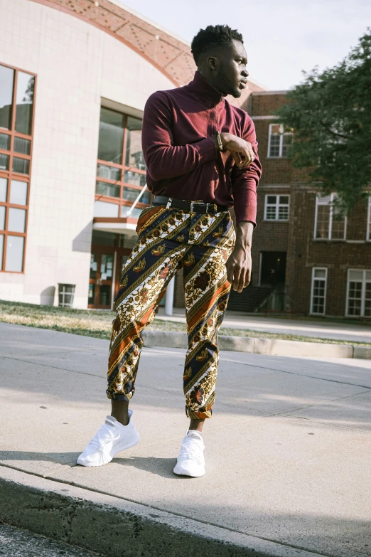 young man in high top sneakers standing on cement curb