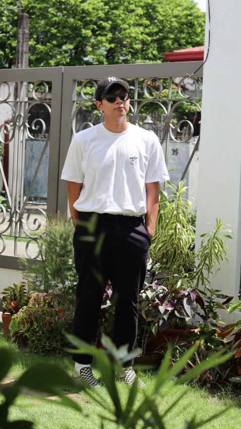 a man in sunglasses stands near some flowers