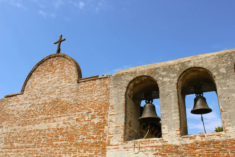 two bells sitting on top of a brick wall