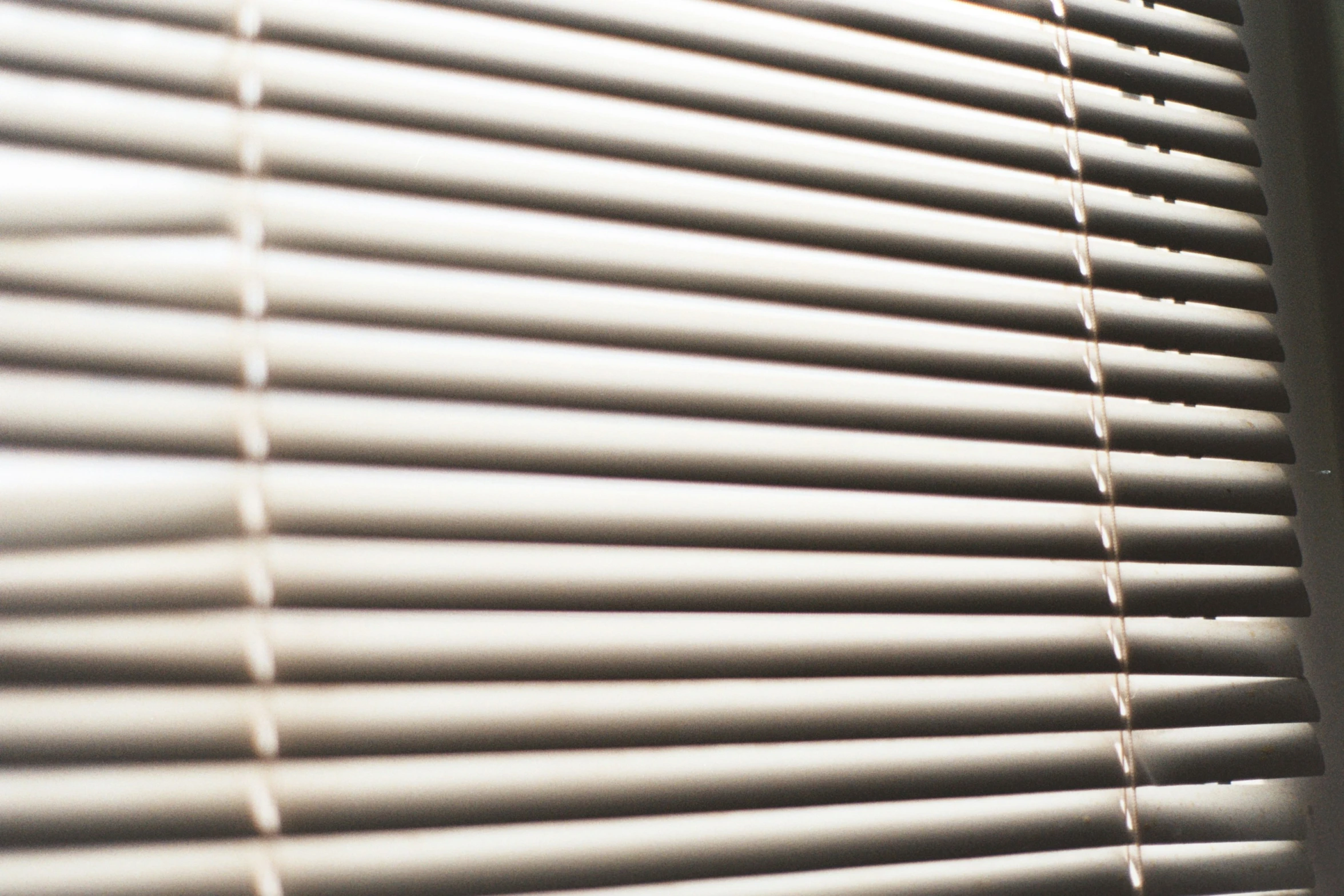 the sun is shining on a window with some blinds closed