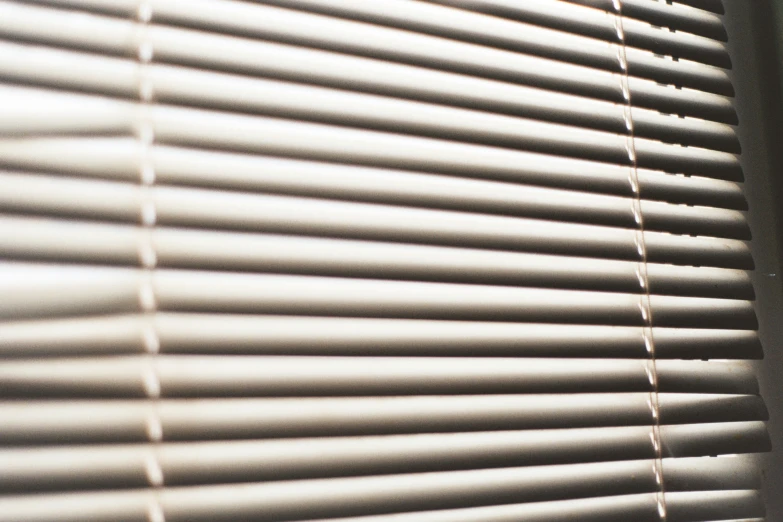 the sun is shining on a window with some blinds closed