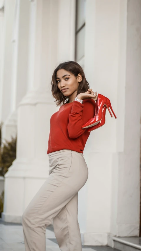 a woman in tight pants poses with a pair of high heels