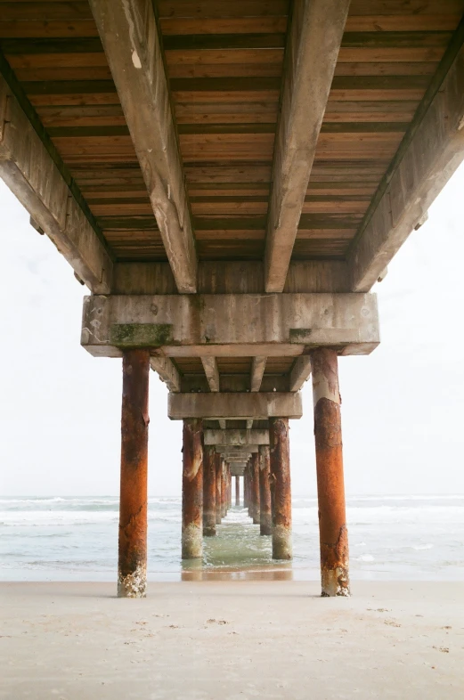 looking down underneath a wooden pier at the beach