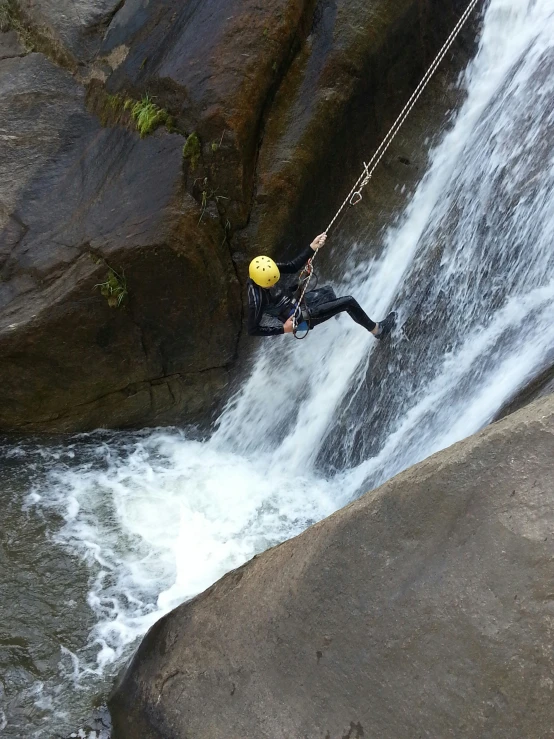 a person in black is being roped over the waterfall