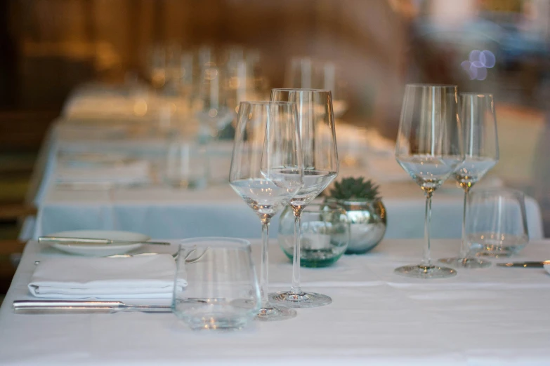 the table is set with many empty wine glasses