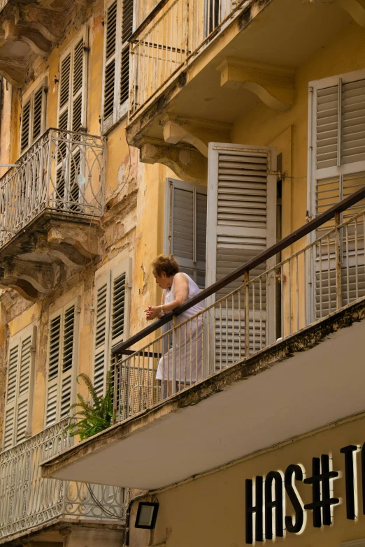 woman standing on balcony next to el sign and balcony area