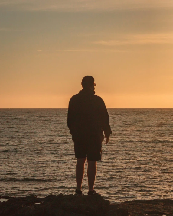 a man standing on top of a rock near the ocean