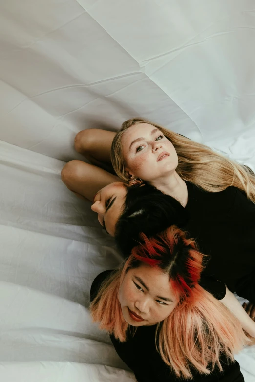 two girls laying on top of a white bed