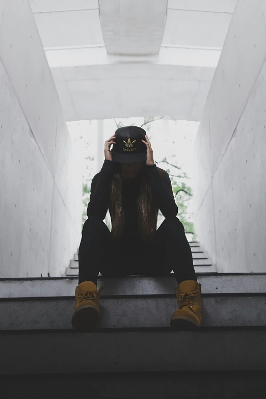 a woman sitting on the side of a stairway with her face in her hands