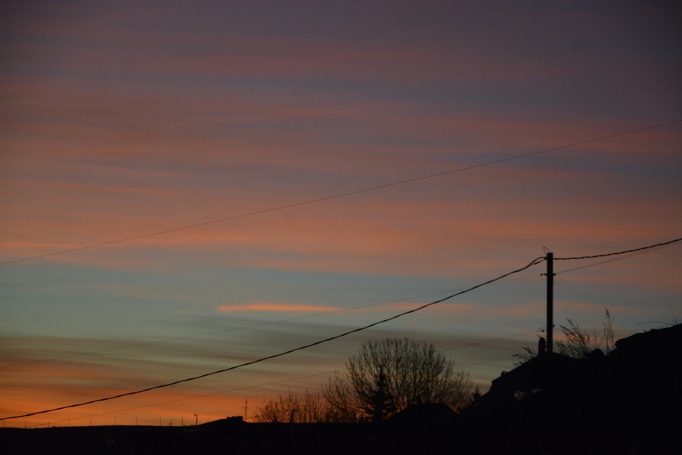 a telephone pole at sunset behind a mountain